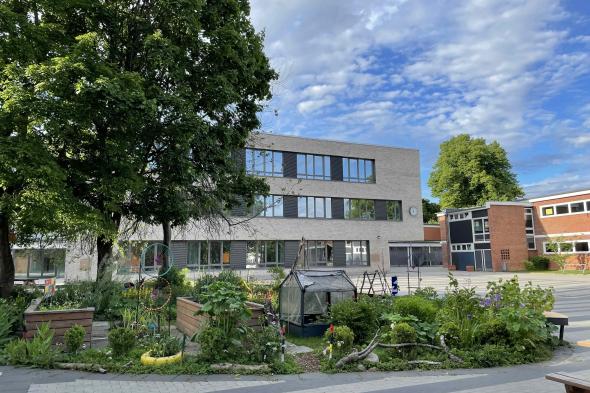 Symbolbild Grün-bunte Schulgarteninseln auf einem Großstadtschulhof